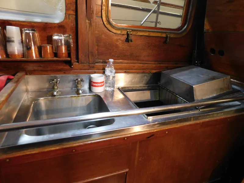 Slide: The Image of 1949 Burger Full Keel Steel Auxiliary Ketch galley with stainless steel sink and wooden cabinetry. - 22