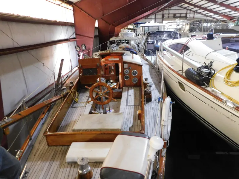 Slide: The Image of 1949 Burger Full Keel Steel Auxiliary Ketch in a boatyard, showcasing classic wooden deck and helm. - 5