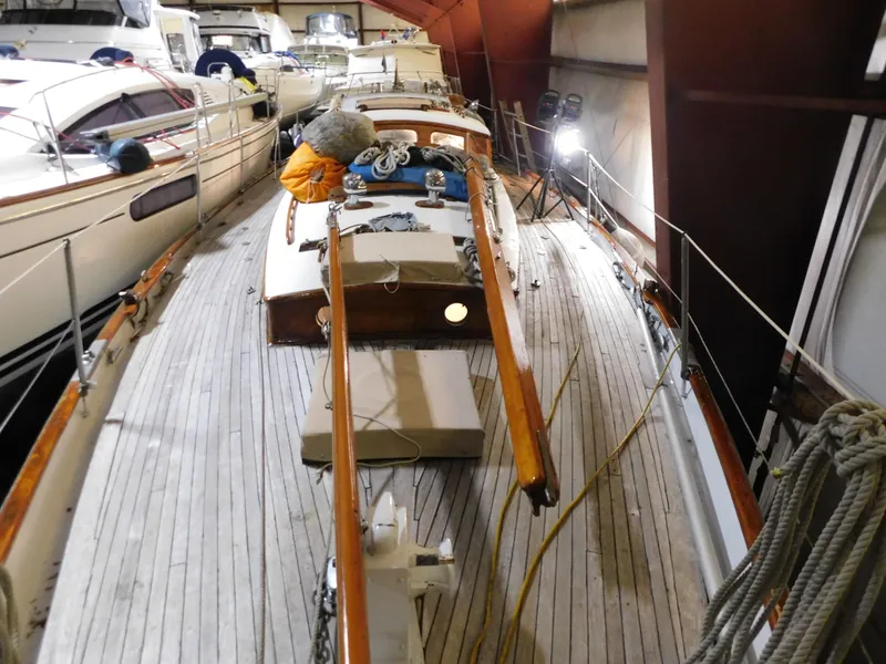 Slide: The Image of 1949 Burger Full Keel Steel Auxiliary Ketch in storage, showcasing wooden deck and rigging. - 8