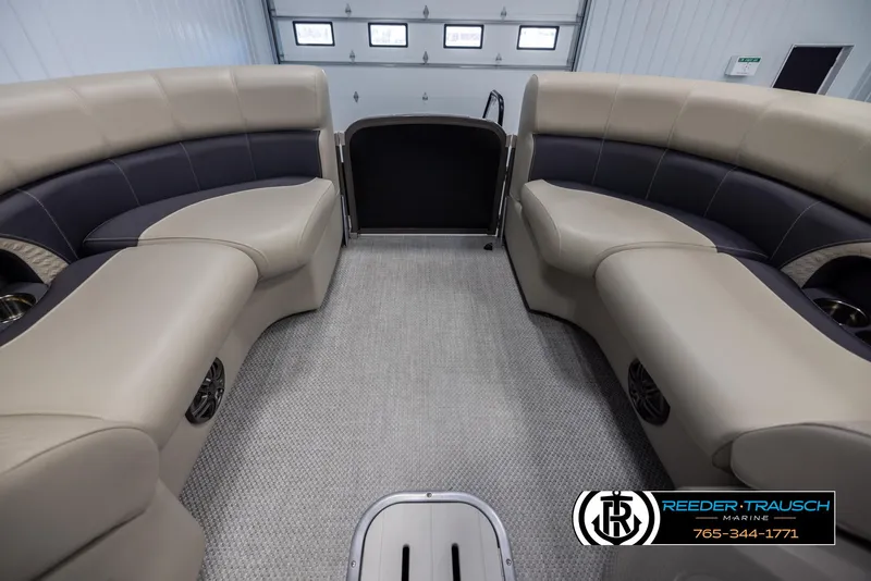 Slide: The Image of 2022 Premier 210 Sunsation pontoon boat interior with beige seating in a showroom. - 18