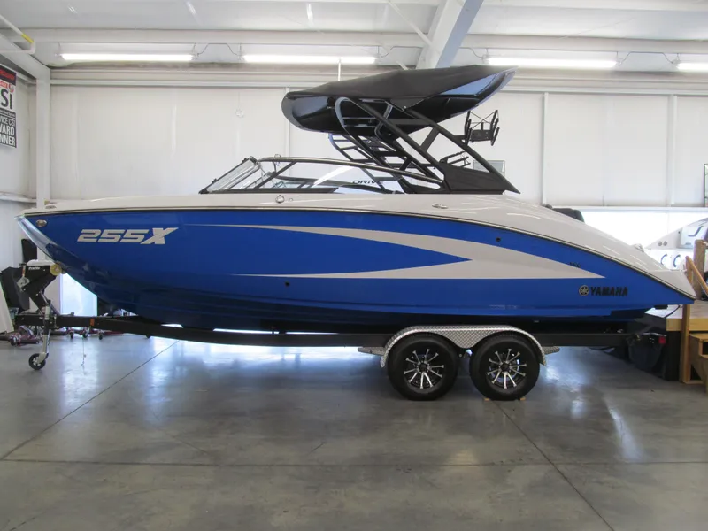 Slide: The Image of 2025 Yamaha Boats 255XD in showroom, blue and white design, on trailer. - 0
