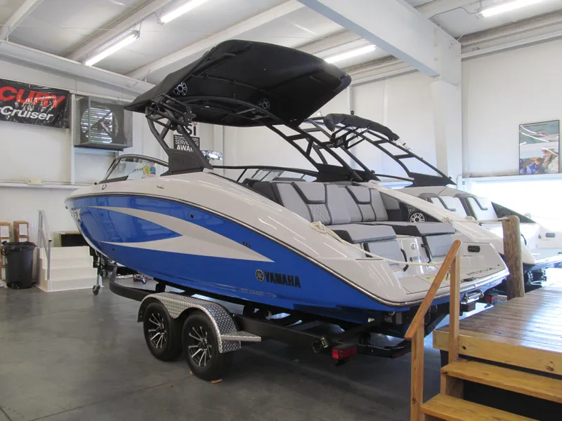 Slide: The Image of 2025 Yamaha Boats 255XD in showroom, blue and white design, on trailer. - 2