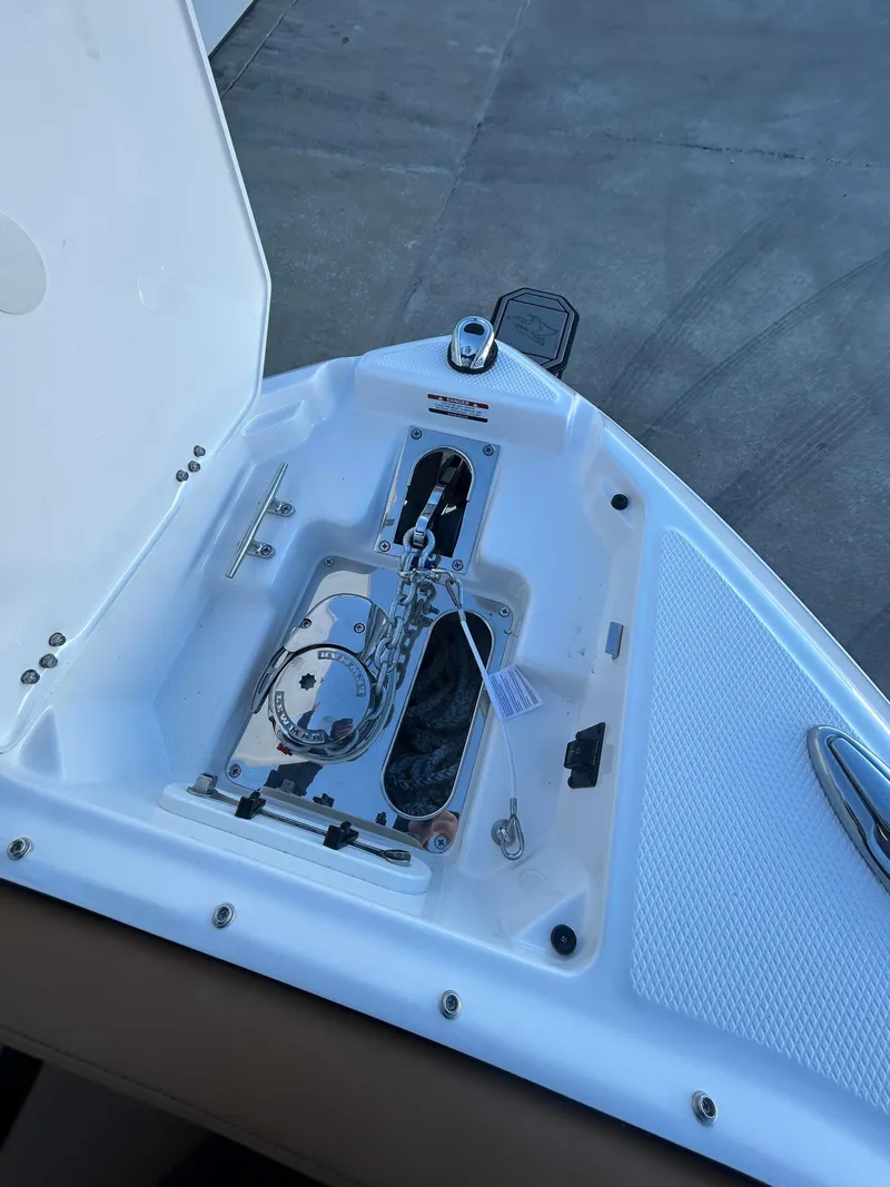 Slide: The Image of 2025 Chaparral 267 SSX boat anchor compartment, open lid, docked on concrete surface. - 10