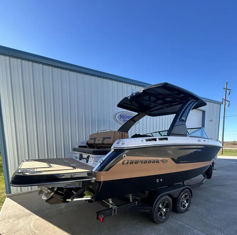 Slide: The Image of 2025 Chaparral 267 SSX boat on trailer, parked outside a metal building. - 2