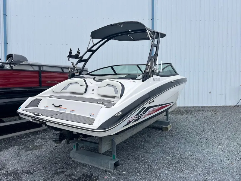 Slide: The Image of 2017 Yamaha AR195 boat with sleek design, parked on gravel near a blue building. - 1