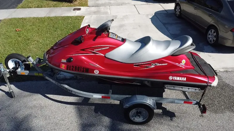 Slide: The Image of 2014 Yamaha WaveRunner VX Cruiser in red on a trailer, parked on a driveway. - 0