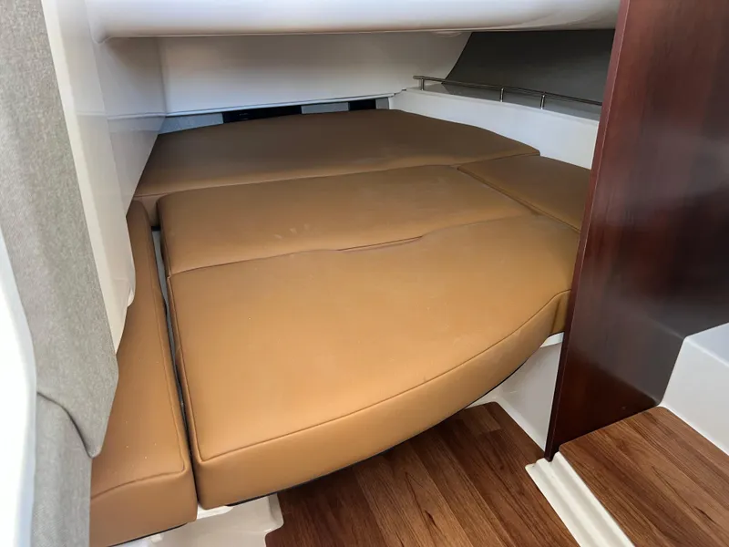 Slide: The Image of 2025 Chaparral 310 OSX cabin interior with tan cushions and wood flooring. - 26