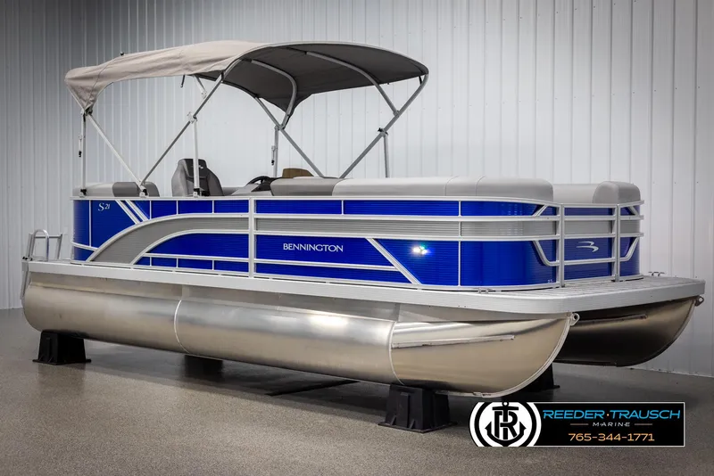 Slide: The Image of 2025 Bennington 21 SSRSE pontoon boat with blue and silver design in showroom. - 2