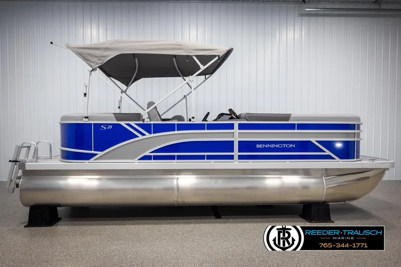 Slide: The Image of 2025 Bennington 21 SSRSE pontoon boat with blue accents and canopy in showroom. - 4