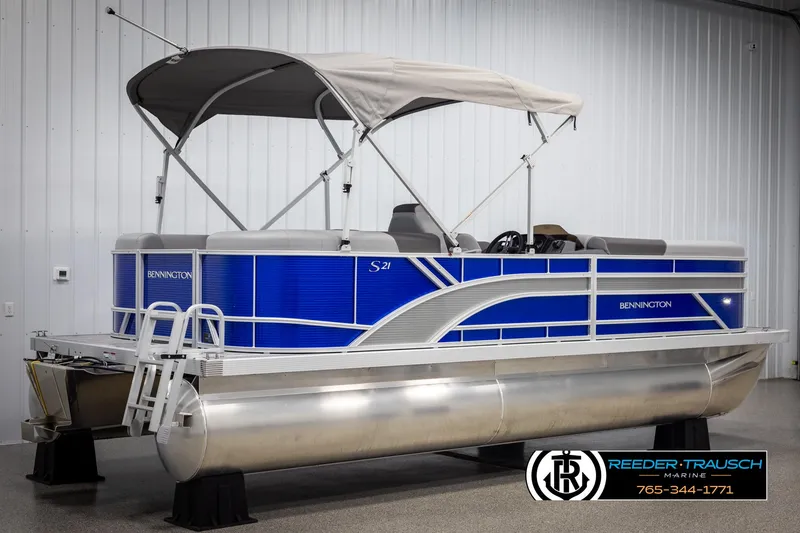 Slide: The Image of 2025 Bennington 21 SSRSE pontoon boat with blue accents and canopy in showroom. - 5