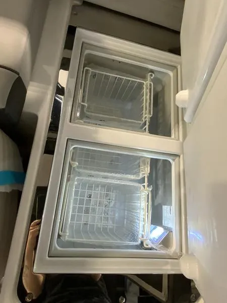 Slide: The Image of Dual-compartment refrigerator in a 2025 Cobalt R35 boat, featuring wire baskets and glass lids. - 9