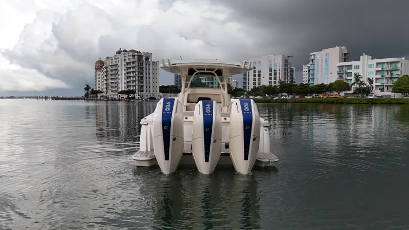 Slide: The Image of 2025 Scout 377 LXF boat with triple engines on calm water, cityscape background. - 11