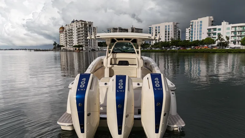 Slide: The Image of 2025 Scout 377 LXF boat with triple 400 V10 engines on a calm waterfront. - 12