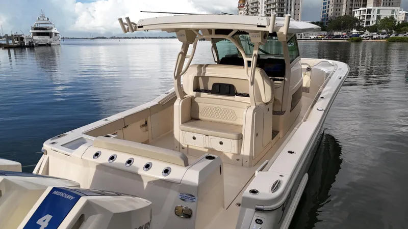 Slide: The Image of 2025 Scout 377 LXF boat docked in a marina with cityscape background. - 14