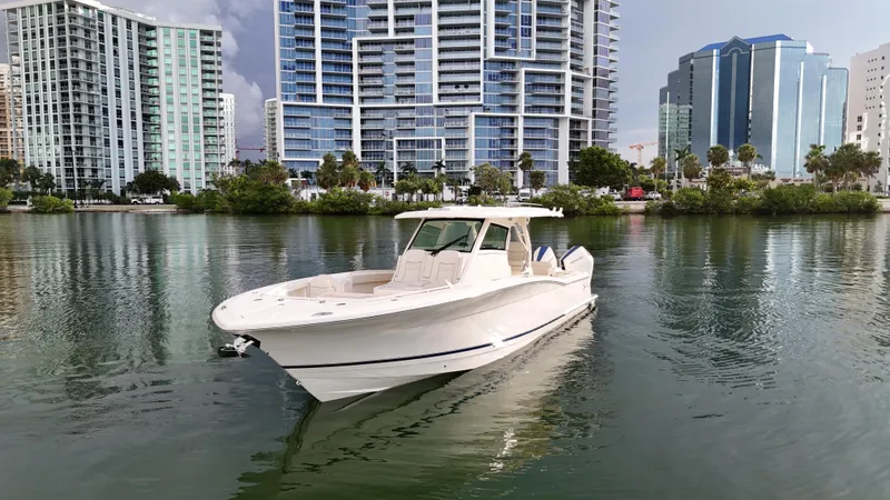 Slide: The Image of 2025 Scout 377 LXF boat on calm water with city skyline background. - 2