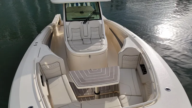 Slide: The Image of 2025 Scout 377 LXF luxury boat interior with seating and table on calm water. - 5