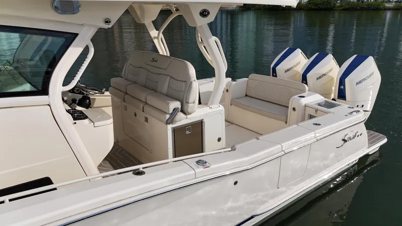 Slide: The Image of 2025 Scout 377 LXF boat with luxurious seating and triple Mercury engines on calm water. - 7