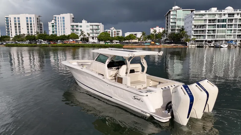 Slide: The Image of 2025 Scout 377 LXF boat on water with modern buildings in the background. - 9