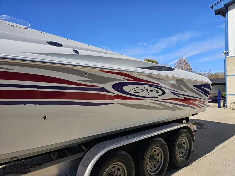 Slide: The Image of 2004 Baja 33 Outlaw boat with vibrant red and purple graphics on a trailer. - 18