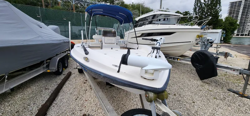 Slide: The Image of 2005 Young Boats Young 20 on trailer, blue canopy, parked beside other boats. - 10