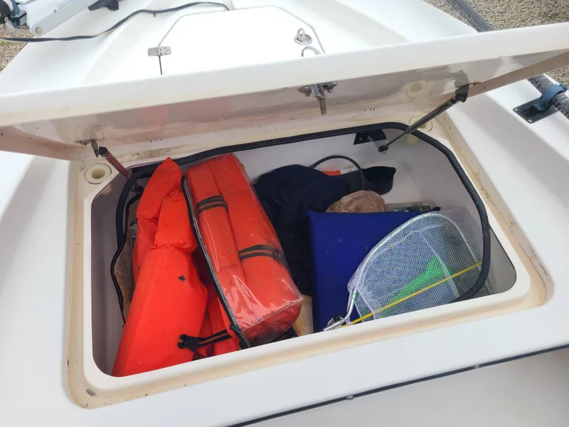 Slide: The Image of Open storage compartment on 2005 Young Boats Young 20, containing life jackets and fishing gear. - 14
