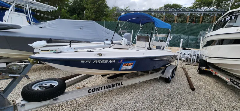 Slide: The Image of 2005 Young Boats Young 20 on trailer, blue canopy, for sale sign, parked in boatyard. - 2