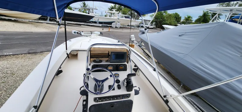 Slide: The Image of 2005 Young Boats Young 20 interior with steering wheel, dashboard, and blue canopy. - 20