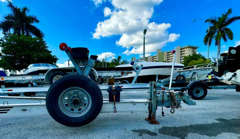 Slide: The Image of Boat trailer REAL X Model R32X 2016 parked under a blue sky with palm trees. - 2