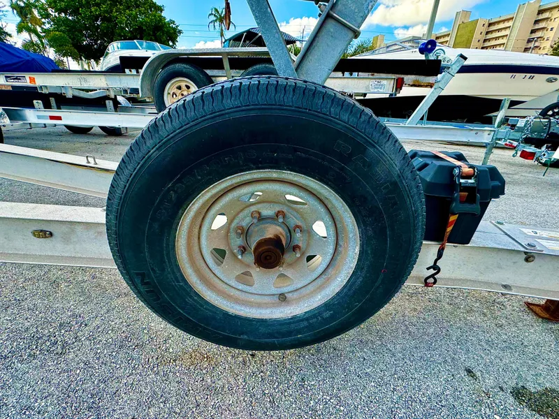 Slide: The Image of 2016 REAL X Model R32X trailer wheel on asphalt, with boats in the background. - 30