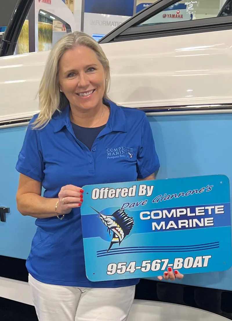 Slide: The Image of Woman holding Complete Marine sign in front of blue and white boat. - 5