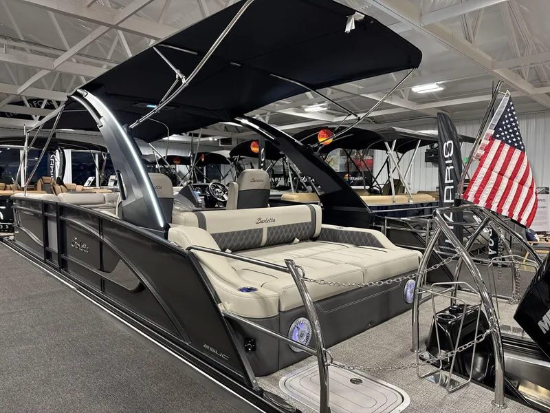 Slide: The Image of 2025 Barletta Lusso L25-UCA pontoon boat with American flag, showcased indoors. - 3