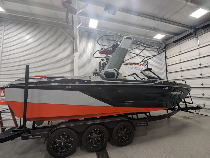 Slide: The Image of 2020 Nautique G23 Paragon boat in a garage, featuring sleek black and orange design. - 1