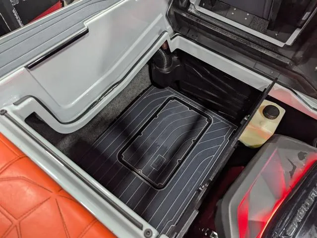 Slide: The Image of 2020 Nautique G23 Paragon storage compartment with orange seating and black flooring. - 16