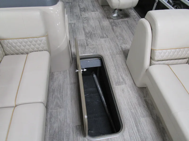 Slide: The Image of 2024 Ranger Reata 243C interior with open floor storage compartment and beige seating. - 12