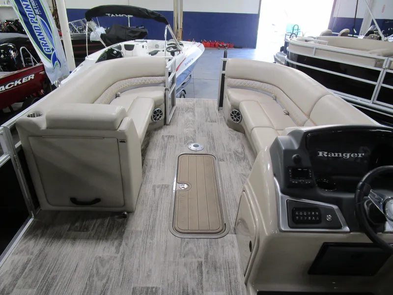 Slide: The Image of 2024 Ranger Reata 243C pontoon boat interior with beige seating and modern dashboard. - 14
