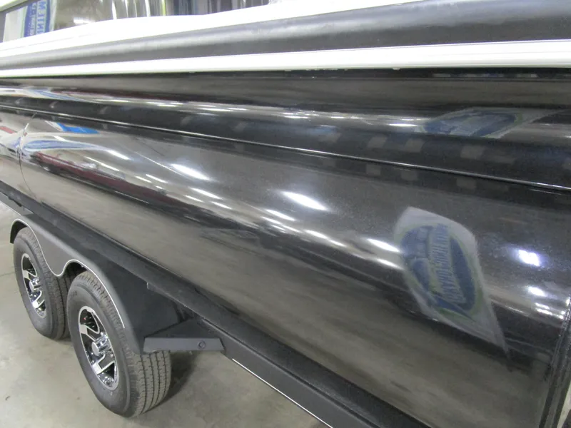 Slide: The Image of 2024 Ranger Reata 243C boat exterior with sleek black finish and dual-axle trailer. - 24
