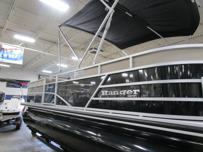 Slide: The Image of 2024 Ranger Reata 243C pontoon boat displayed indoors with canopy. - 3