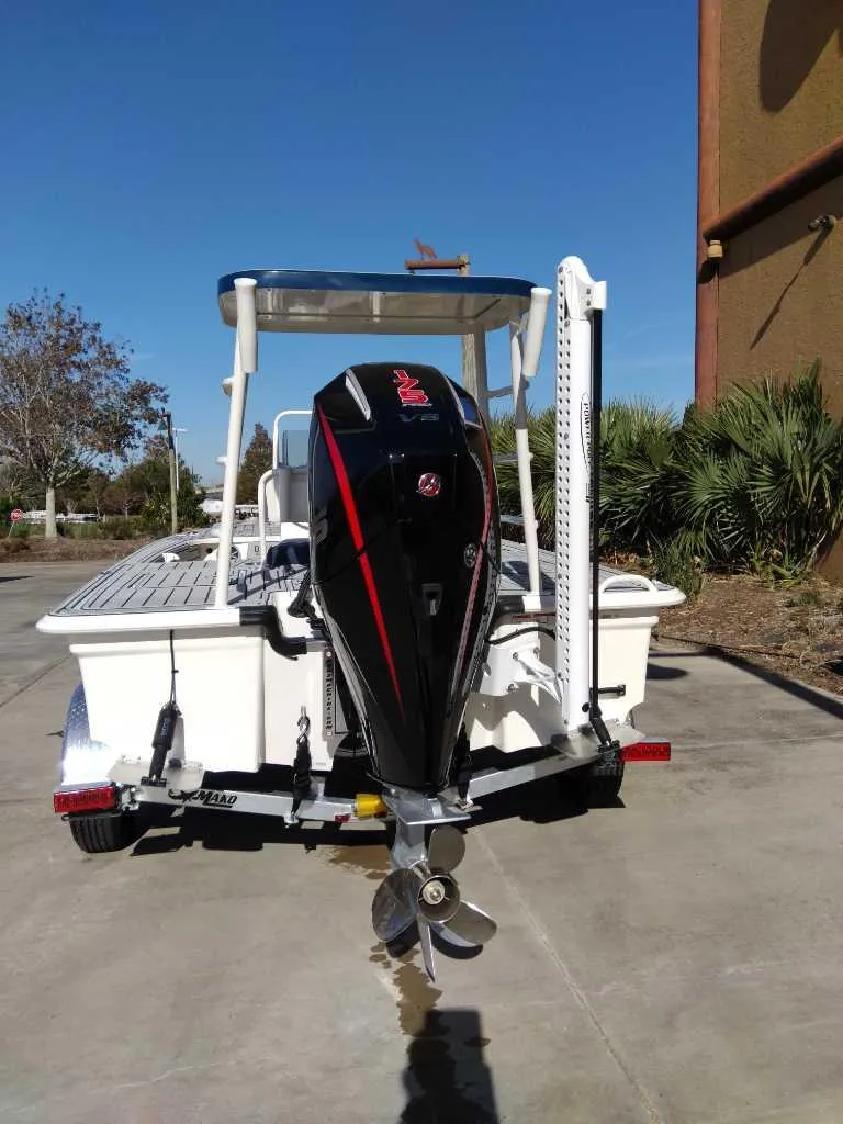 Slide: The Image of 2025 Mako 18 Pro Skiff Patriot Edition boat with outboard motor, parked outdoors. - 3