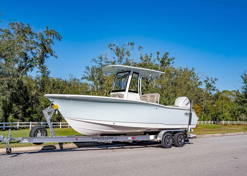 Slide: The Image of 2025 Sea Hunt Ultra 239 SE boat on trailer, parked on a sunny road. - 1