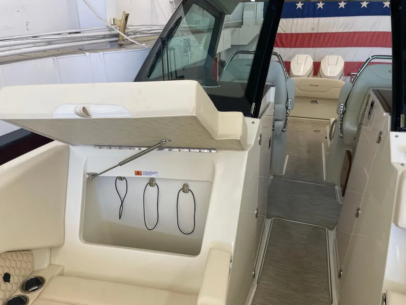 Slide: The Image of 2024 Chris-Craft Calypso 32 interior with seating and storage, American flag backdrop. - 35