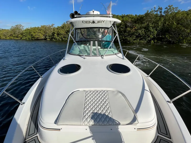 Slide: The Image of 2005 Century 3200 Walk-Around boat on water, front view, clear sky, lush greenery. - 13