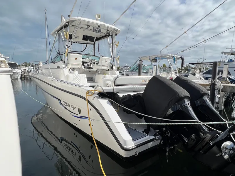 Slide: The Image of 2005 Century 3200 Walk-Around boat docked in marina, featuring dual outboard motors. - 43