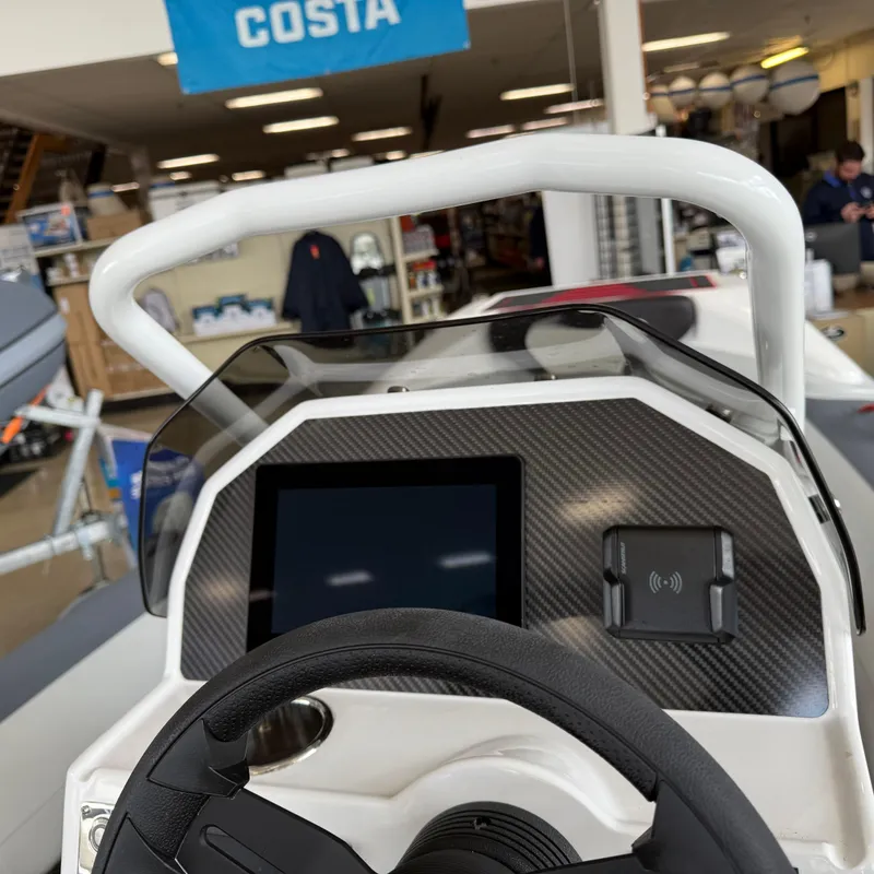 Slide: The Image of Highfield 420 Velox 2025 boat dashboard with steering wheel and digital display in showroom. - 6