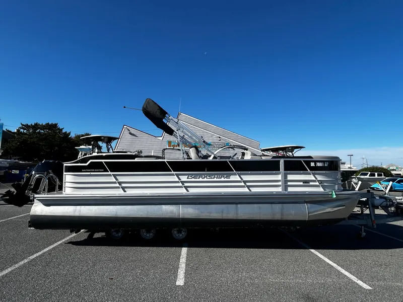 Slide: The Image of 2024 Berkshire 24RFC LE 2.75 pontoon boat parked in a lot under clear blue sky. - 0