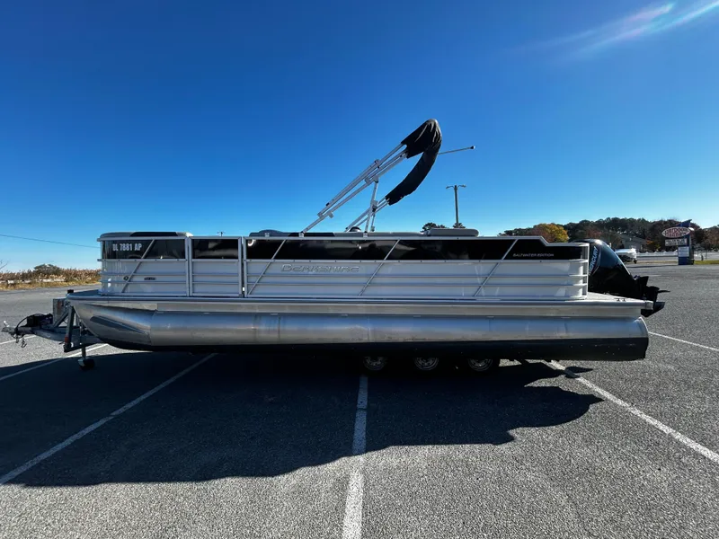 Slide: The Image of 2024 Berkshire 24RFC LE 2.75 pontoon boat parked in a lot under clear blue sky. - 3