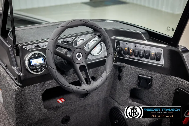 Slide: The Image of 2025 Lund 1875 Impact XS boat dashboard with steering wheel and control panel. - 24