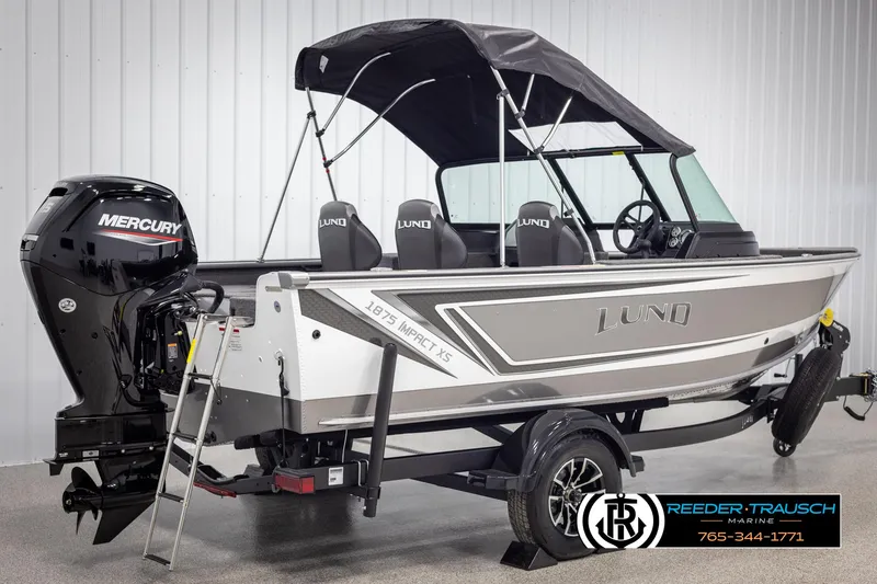 Slide: The Image of 2025 Lund 1875 Impact XS boat with Mercury engine and canopy in showroom. - 5