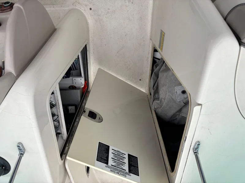 Slide: The Image of 2004 Sea Ray 200 Sundeck storage compartment with open hatch and visible interior items. - 9