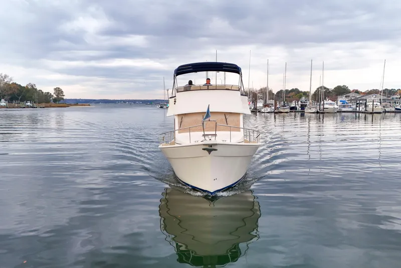 Slide: The Image of 2005 Mainship 34 Trawler cruising on calm waters near a marina. - 1