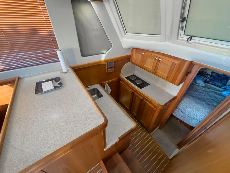Slide: The Image of 2005 Mainship 34 Trawler interior kitchen with wood cabinetry and compact design. - 12